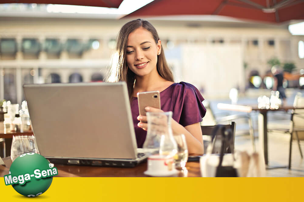 Preço da Mega Sena Mulher bonita está verificando preços da Mega Sena em seu laptop e celular.