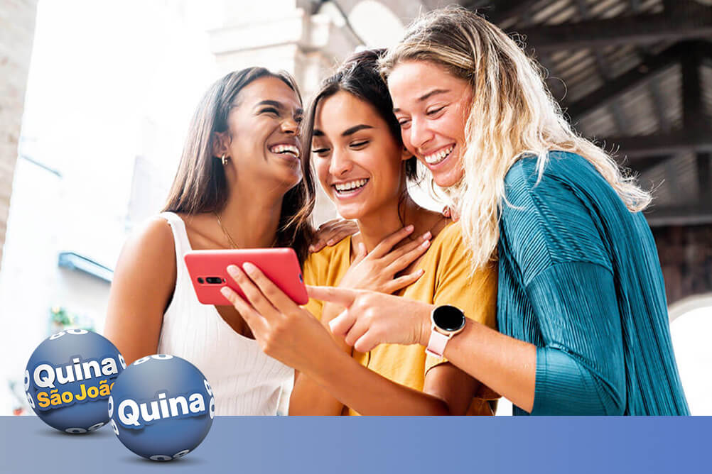 Três amigas sorrindo ao olhar suas apostas ganhadoras depois de aprender como jogar bolão da Quina e Quina de São João.