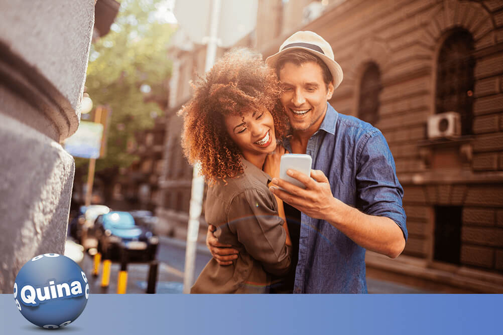 Casal confere no smartphone como jogar na Quina pela internet.