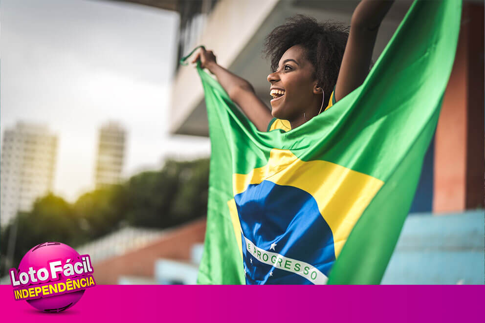 Mulher sorrindo com bandeira do Brasil simbolizando sorte nos números mais sorteados da Lotofácil da Independência.
