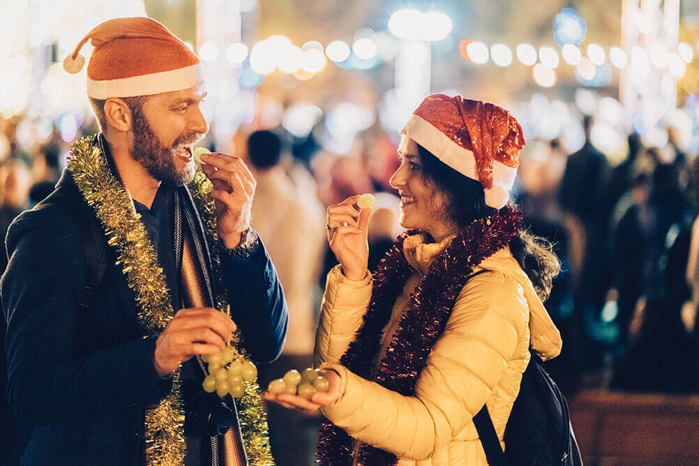 Amigos vestidos com gorro de Papai Noel, comem 12 uvas durante a virada de ano na Espanha.